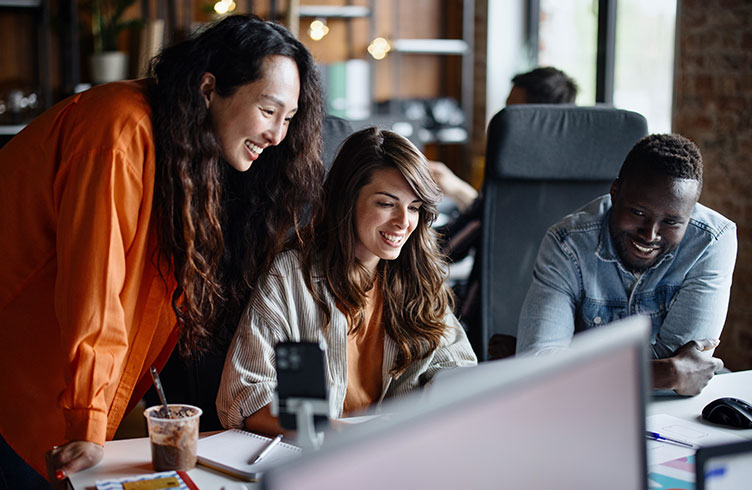 diverse group of C-suite recruitment employees collaborating at a computer